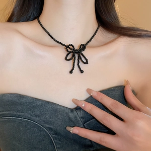 Detailed close-up of a black beaded choker necklace featuring a 3D woven ribbon bow design