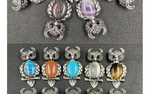 Macro view of crystal owl pendants showing textured metal feathers and colorful gemstones