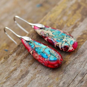Macro shot of bohemian teardrop earrings featuring colorful imperial stone and silver hooks
