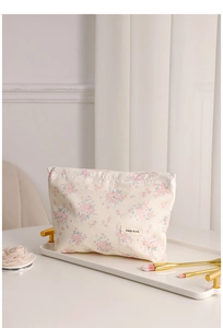 Detailed close-up of a floral canvas makeup bag with pink roses and woven logo label