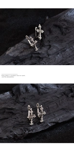 Close-up of retro silver cross earrings with gothic floral engravings on wood background