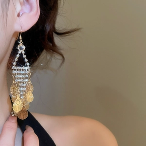 Detail of elegant gold leaf tassel earrings with sparkling rhinestones and metal sequins
