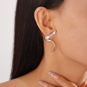 Close-up of minimalist silver spiral ear crawler on model showing polished metallic luster