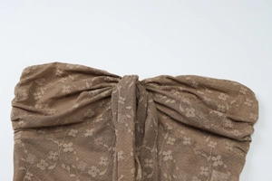 Détail du haut bandeau en dentelle marron avec nœud central et motifs floraux délicats