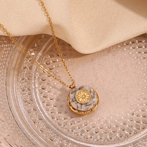 Detail of 18K gold plated sunburst pendant necklace with natural marble stone inlay