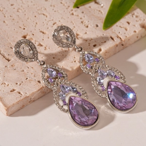 Detailed view of silver drop earrings with large purple crystals and sparkling diamonds