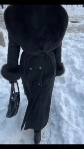 Détails d'un manteau noir en laine avec col et poignets en fourrure et ceinture à nouer