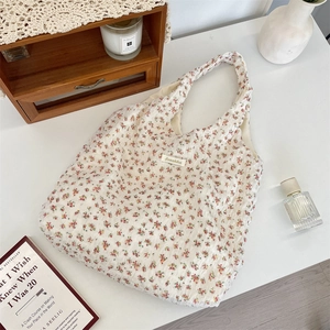 Detailed close-up of floral canvas tote bag with Sosakka label on a wooden desktop