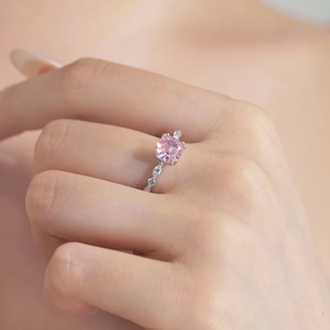 Macro view of a square-cut pink zircon ring with diamond-encrusted silver band on finger