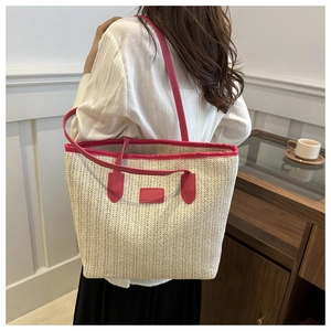 Close-up of beige woven straw tote bag with vibrant magenta leather handles and trim