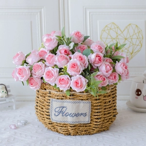 Pink artificial roses in a rustic straw woven basket with a Flowers fabric label