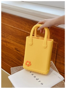 Detail der gelben EVA-Strandtasche mit süßem orangefarbenem Blumenzubehör und Griff