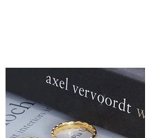 Macro detail of gold-plated wavy rings stacked on artistic books for a chic look