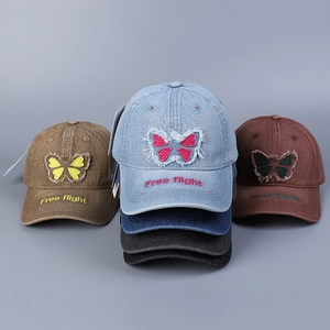 Detail of embroidered butterfly and Free flight text on washed denim baseball caps