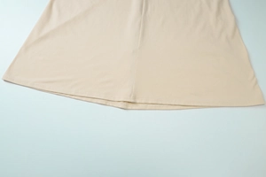 Detailed close-up of the double-stitched hem and soft fabric texture on a beige maxi dress