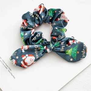 Detail of Christmas velvet scrunchie with festive cartoon patterns and knotted bow style