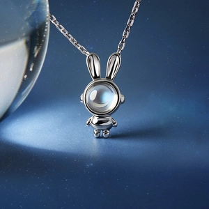 Macro shot of silver astronaut bunny pendant featuring a glowing moonstone on starry background