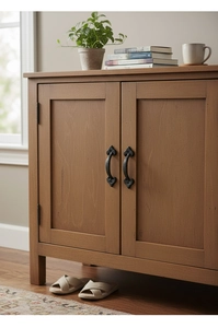Detail of vintage black cast iron handles on a minimalist natural wood storage cabinet