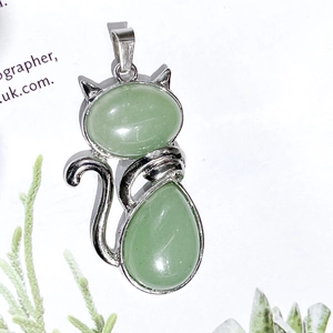 Detail of silver cat pendant with light green natural crystal stones on white surface