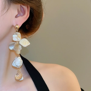 Detail of long drop earrings featuring irregular shell fragments and gold seashell pendants