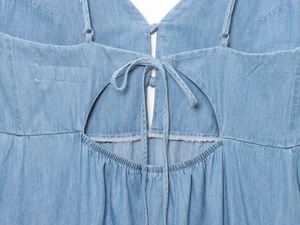 Detail of blue denim midi dress featuring a criss-cross tie-back and cutout design
