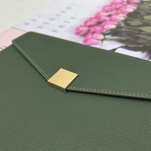 Detailed close-up of dark green litchi grain leather notebook with gold buckle