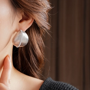 Detail of silver brushed metal teardrop earring with delicate white pearl accents