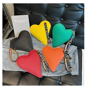 Variété de sacs à main colorés en forme de cœur sur une veste en jean et un canapé en cuir
