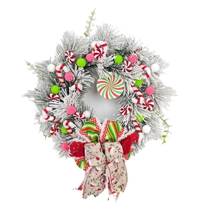 Christmas wreath with candy canes, peppermint discs and colorful ornaments on snowy cedar