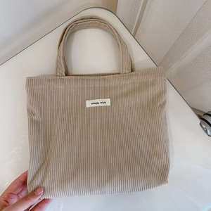 Detail of camel corduroy tote bag featuring a small simple wish woven label and soft texture
