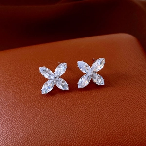 Macro shot of silver flower earrings with marquise-cut zircons on a leather background