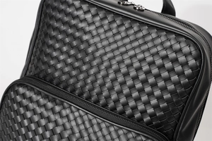Detail of black woven leather backpack showing premium texture and metallic zipper hardware