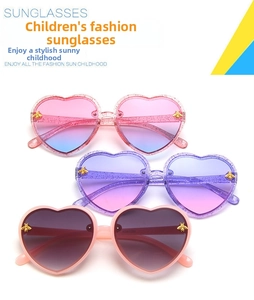 Close-up of heart-shaped kids sunglasses with glitter frames and gold bee accents