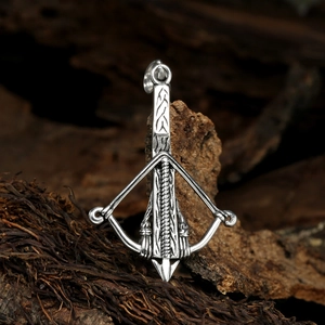 Detailed macro view of a silver bow and arrow pendant on a rustic natural bark background