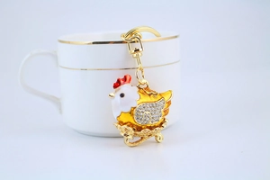 Detailed view of a golden rooster keychain featuring sparkling rhinestones and enamel finish