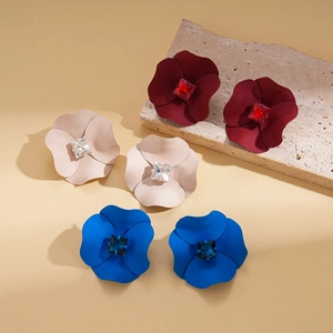 Three pairs of matte flower stud earrings with square crystals in red, beige and blue colors