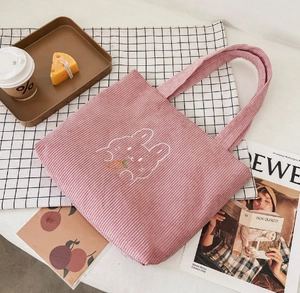 Detail view of pink corduroy tote bag featuring an embroidered rabbit with a carrot