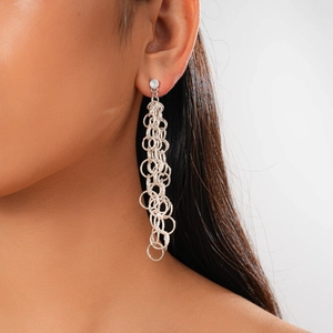 Détail de boucles d'oreilles pendantes avec cercles argentés et clou serti d'un zircon brillant