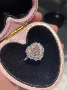 Primo piano di un anello con diamante rosa a cuore e montatura a pavé in una scatola