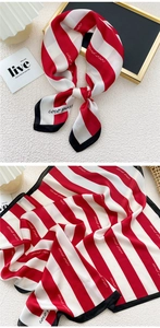 Close-up of red and white striped silk scarf with black borders and elegant printed details