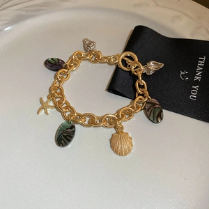 Detailed close-up of golden ocean-themed bracelet with seashell and starfish charms