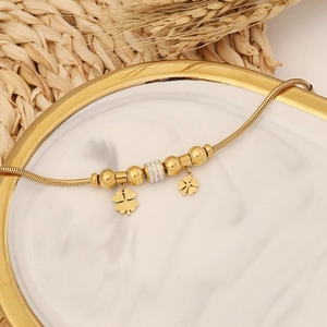 Détail du trèfle doré et perle pavée sur bracelet à chaîne serpent élégant