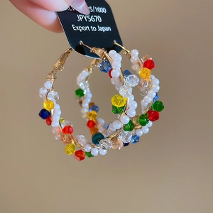 Close-up of bohemian 925 silver hoop earrings with colorful beads and gold wire wrap