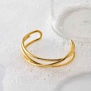 Minimalist multi-layer gold wrap bangle in stainless steel on white textured background