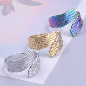 Detail view of wing-shaped stainless steel rings in silver, gold, and rainbow finishes