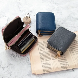 Tres tarjeteros de cuero granulado azul, gris y rosa con doble cremallera dorada