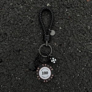 Braided leather keychain with Monte Carlo poker chip, heart and dice charms on dark surface
