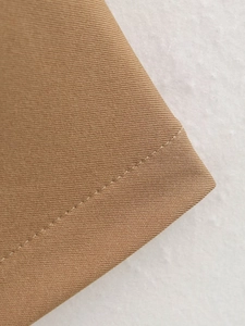 Close-up of khaki pleated knit fabric showing fine stitching and twill texture details