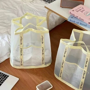 Detail of creamy white mesh storage bag with yellow handles and 'A Better Life' text