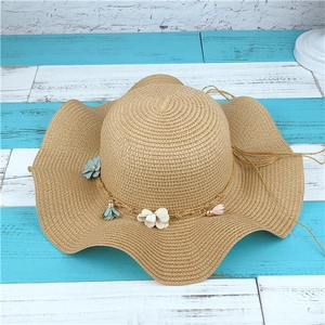 Détail du chapeau de paille à bord ondulé avec des décorations florales colorées